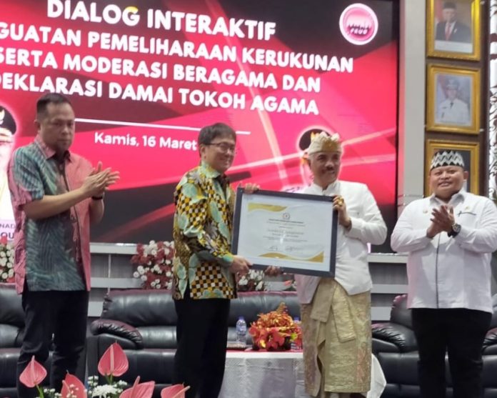 Ketua Asosiasi FKUB Indonesia Ida Pangelingsir Agung Putra Sukahet yang didampingi Wakil Sekretaris Jenderal Pdt. Samuel D. Luas menyerahkan penghargaan kepada Walikota Manado Andrei Angouw dan Wakil Walikota Manado dr. Richard Sualang, di Ruang Serbaguna Kantor Walikota Manado, Kamis (16/3). (Foto:Istimewa)