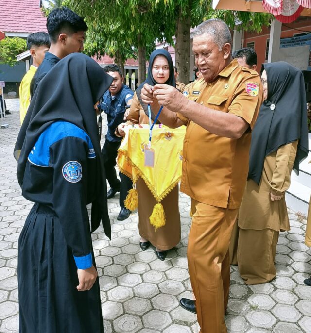 Plt.Kadis Dikpora Tojo Una-Una Burhanudin Lahay saat melakukan pengalungan tanda peserta siswa di SMK Negeri I Ampana beberapa waktu lalu