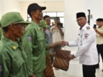 Bupati Bolaang Mongondow Timur Oskar Manoppo menyerahkan bendera Satlinmas kepada perwakilan anggota usai pengukuhan Satuan Perlindungan Masyarakat dan Relawan Pemadam Kebakaran se-Kabupaten Boltim, Rabu, 29 Oktober 2025, di halaman Kantor Bupati Boltim. (Foto: Humas Pemkab Boltim)